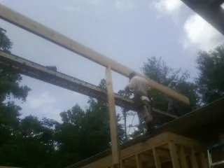 Carpenter setting a ridge beam over a new addition frame — Ice Dam Removal by Roofing Brothers in Michigan Center