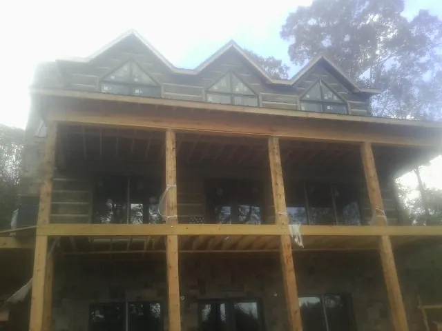 Dormers and porch framing on a large log home under construction — Roof Coating work by our crew in Michigan Center