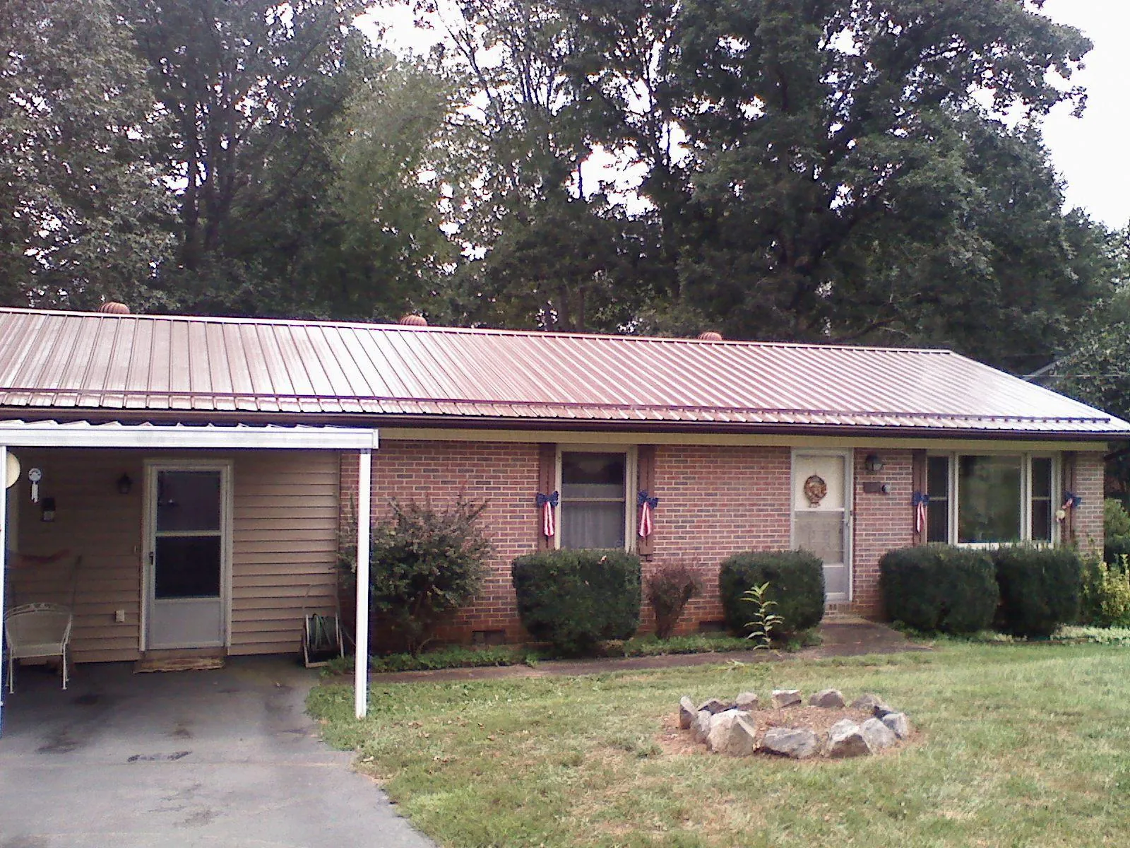 Bronze metal roof and carport on a brick ranch home — Roof Repair work by our crew in Michigan Center