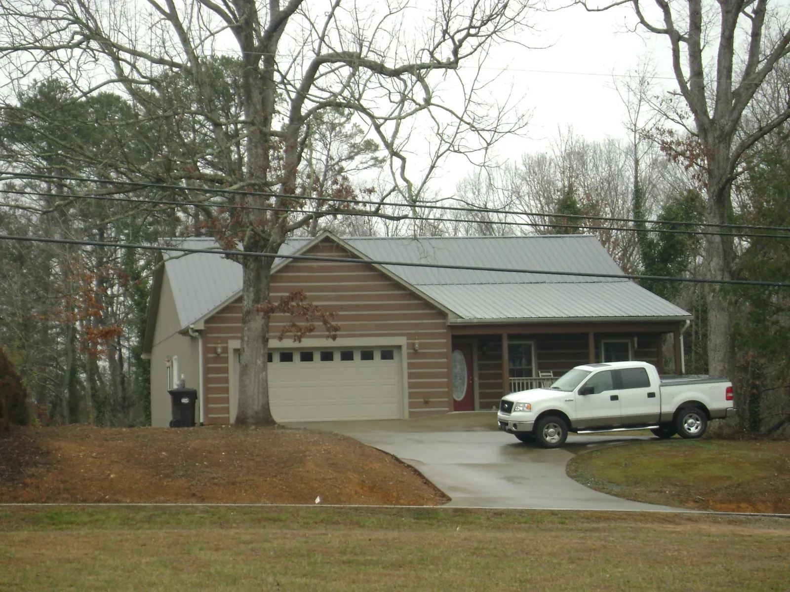 Gray metal roof on a log sided house with an attached two car garage in Michigan Center