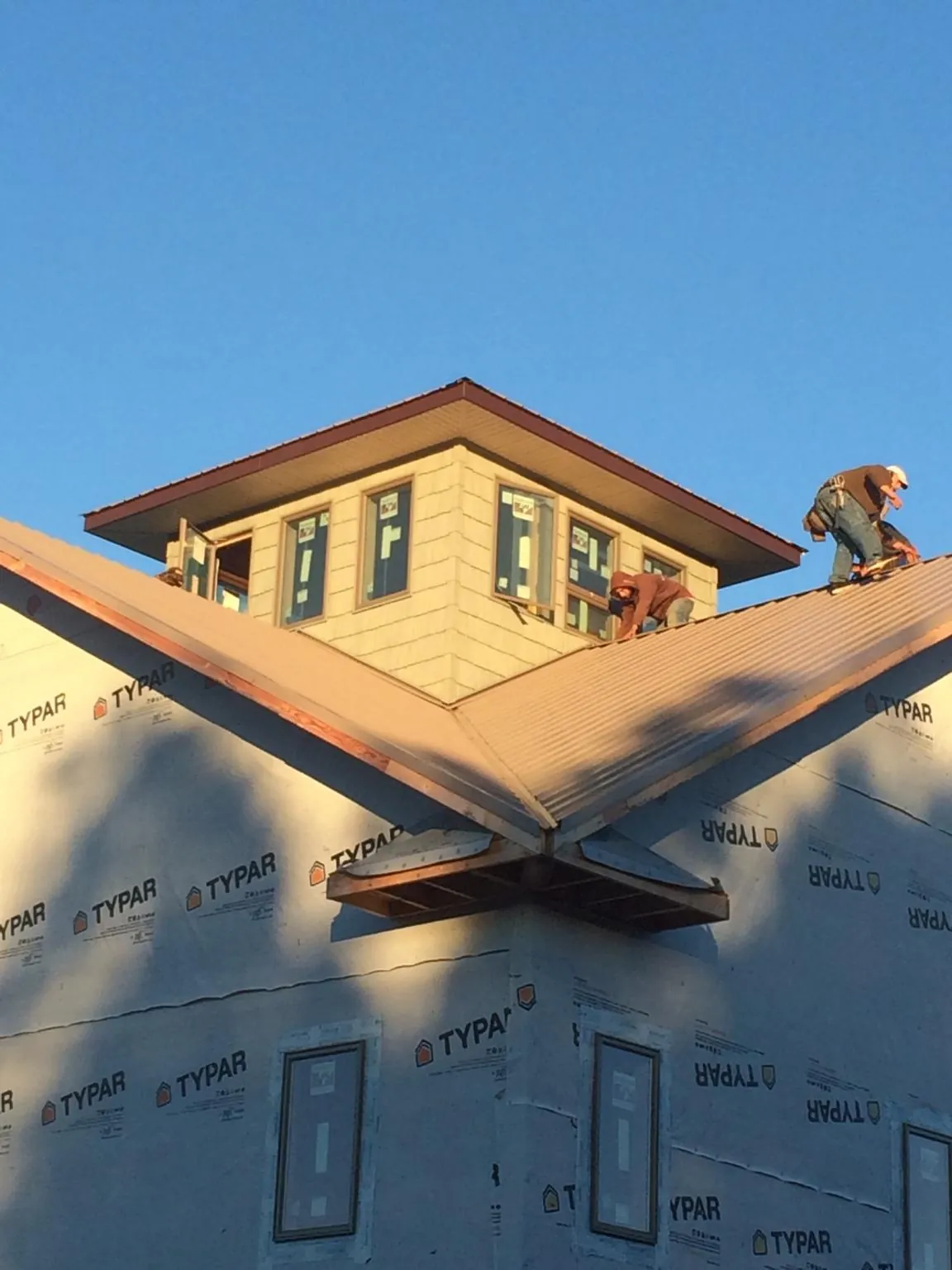 Roofers working around a rooftop cupola on a new metal roof at sunset — Roof Waterproofing in Michigan Center by Roofing Brothers